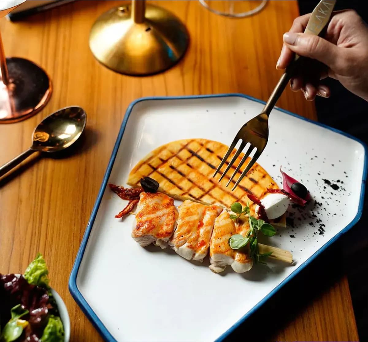 Grilled fish plated on a slate dish with fork