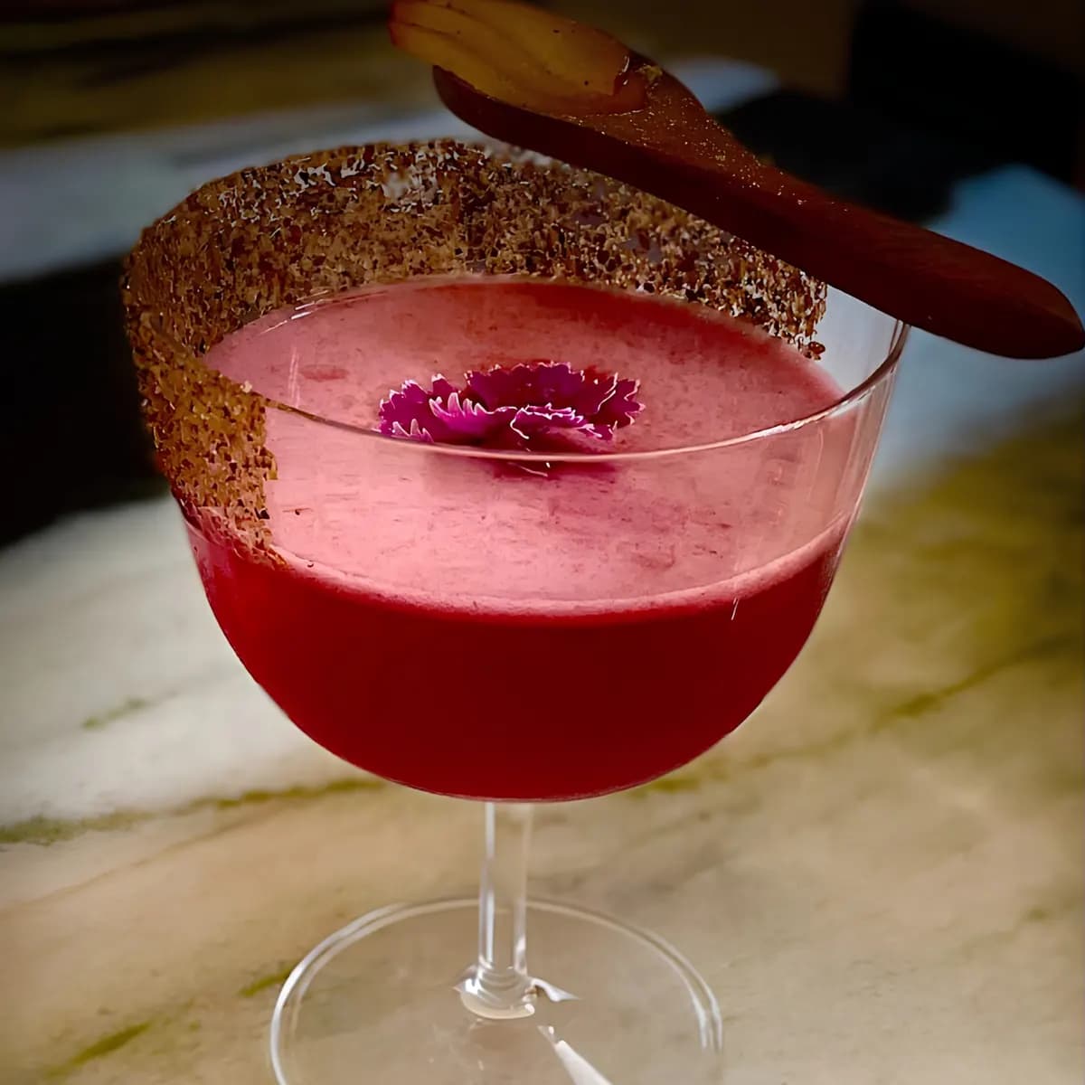 Pink sour cocktail with a sugared rim in a coupe glass