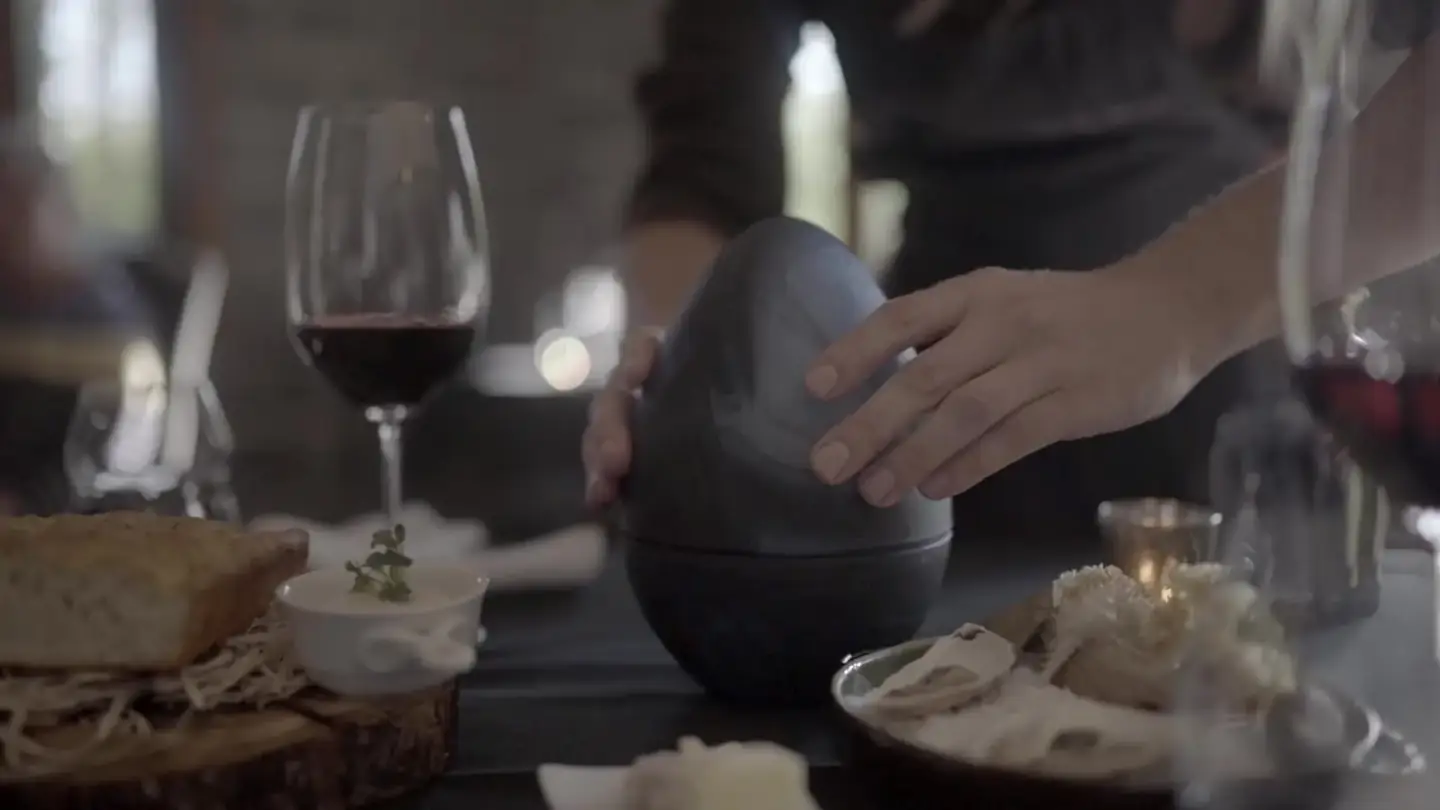 Smoke lifting off a plated dish beside a glass of red wine