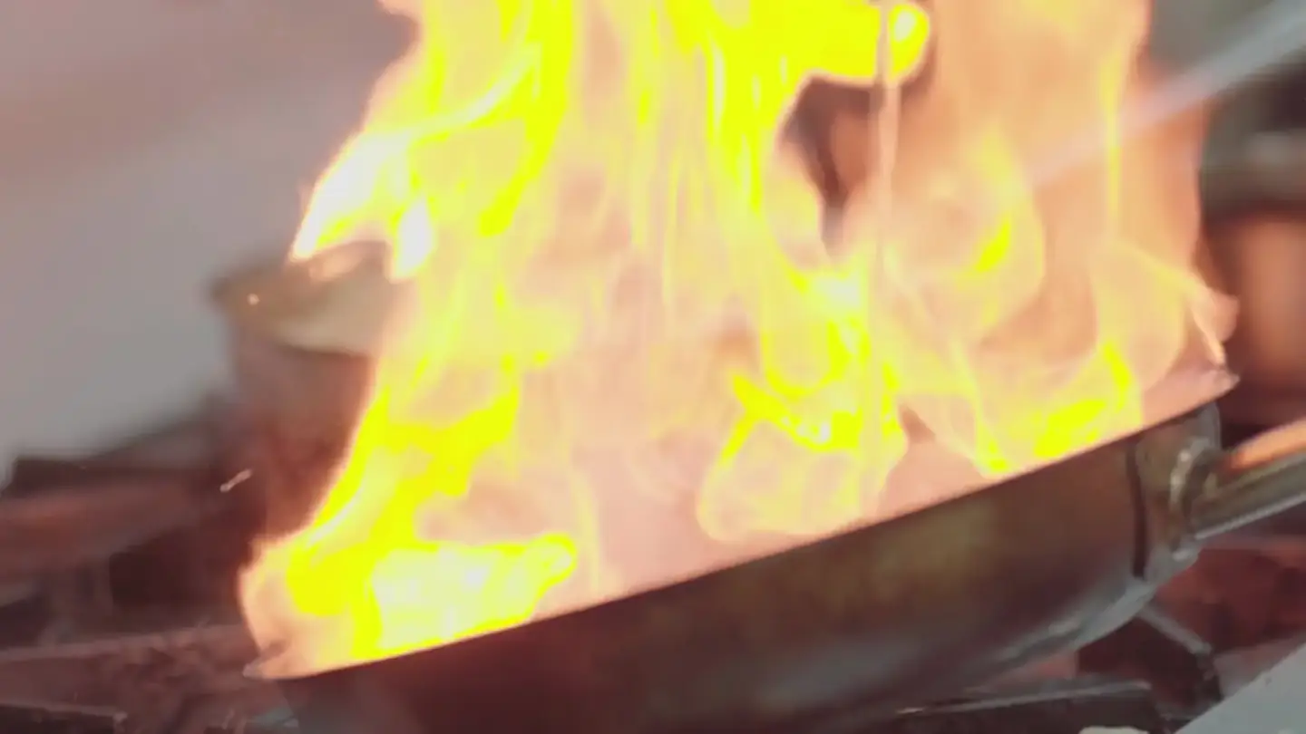 Flames rising from a pan in a professional kitchen