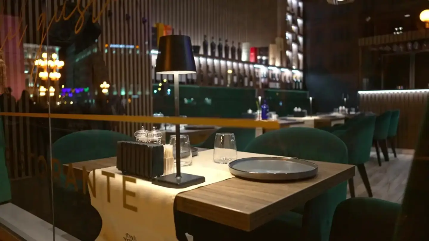 Modern restaurant interior at night with green chairs and warm lighting