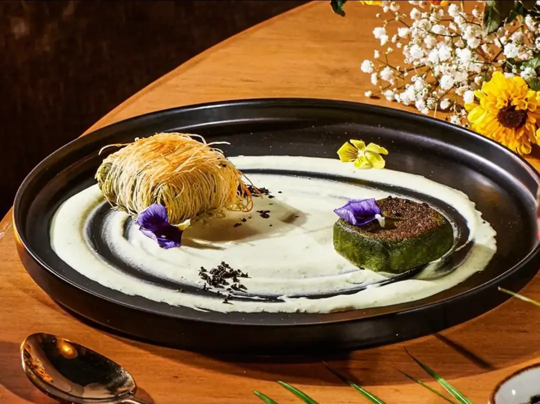 Plated dessert on a black platter with cream swirl